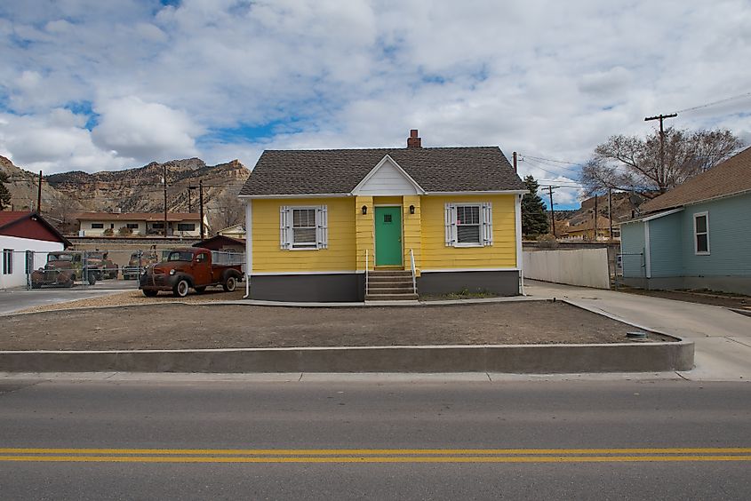 A small yellow hut in Helper, Utah, with the mountains as backdrop