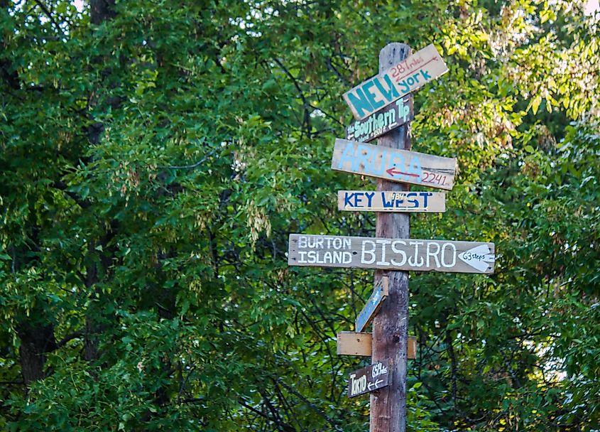 A colorful sign on Burton Island in Vermont that tells you how far it is to the bistro, New York City, Key West, and Aruba.