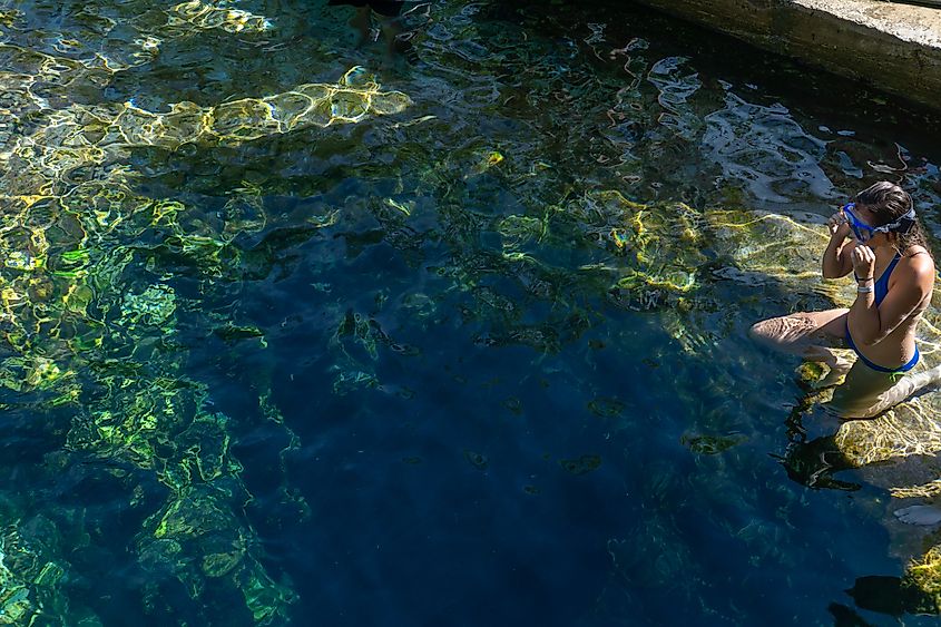 A girl adjusts her goggles as she prepares for a dive down Jacob's Well.