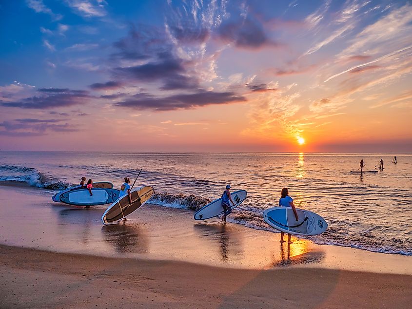 A group of young women with paddle boards preparing to set out at sunrise on Bethany Beach, Delaware