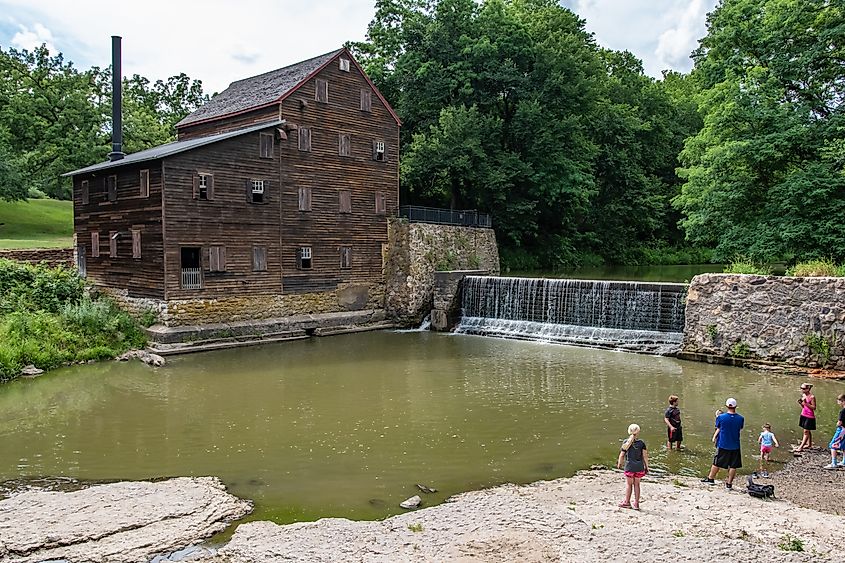 A family looks across the water to the historic Pine Creek Gristmill in Muscatine, Iowa.