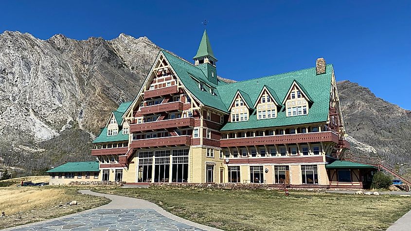 A large, Swiss-chalet style hotel stands before a mountain range. 