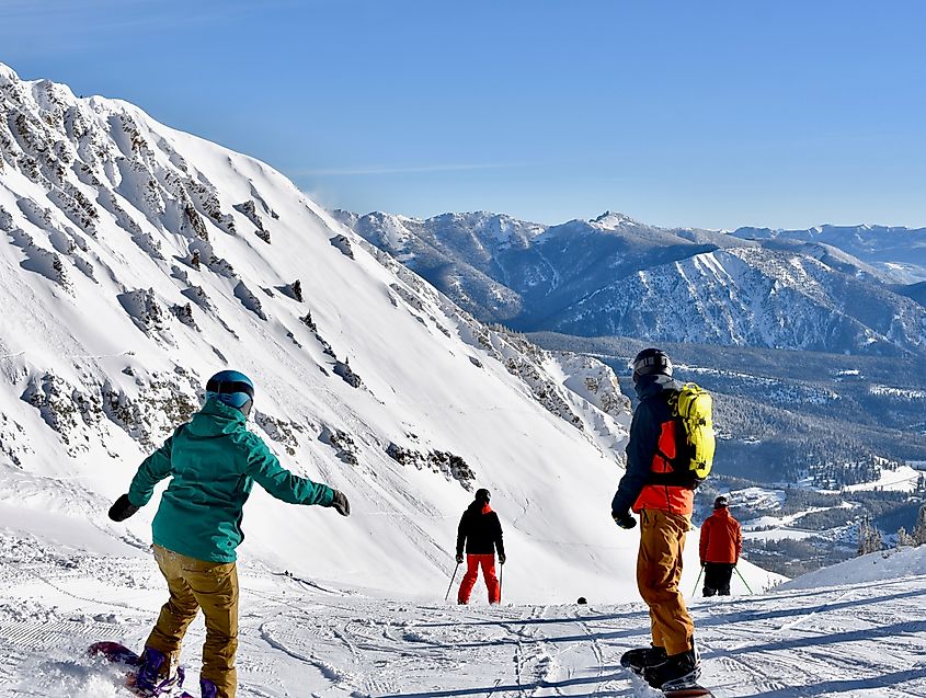 Skiers and snowboarders going over the edge at Big Sky ski resort, Montana.