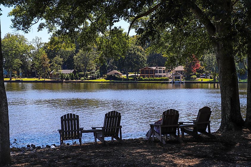 People relaxing in lawn chairs on the grassy banks of Lake Peachtree in Peachtree City, Georgia.