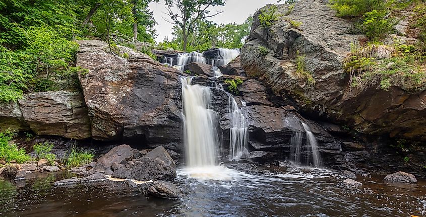 Waterfall cascading over rocky ledges at Eightmile River, surrounded by lush green trees at Chapman Falls in Devil's Hopyard State Park, East Haddam, Connecticut.