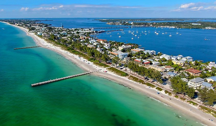 Aerial view of Cortez beach with sand beach and little wood pier on blue water, Anna Maria Island, Florida.