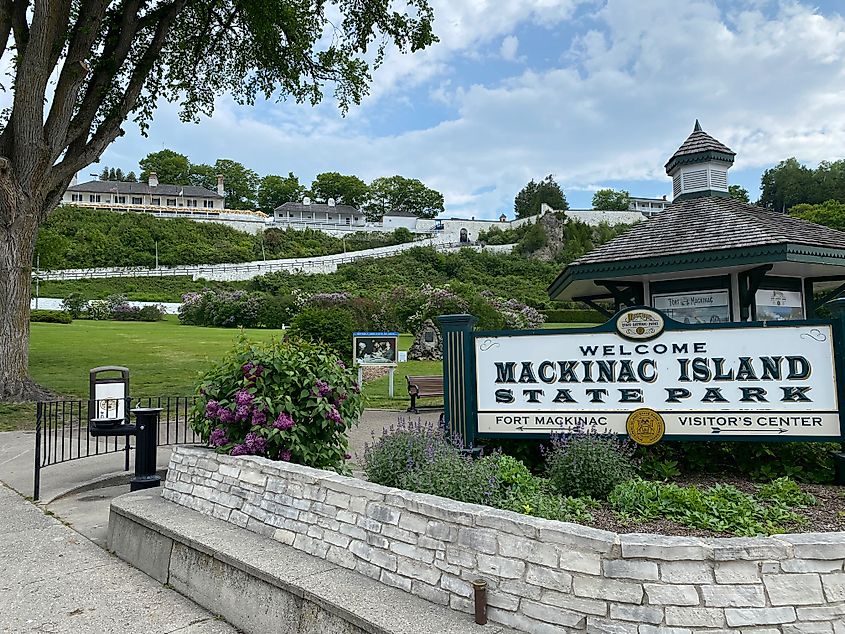 Fort Mackinac stands above the Mackinac Island State Park sign. Bright green Marquette Park sits in between