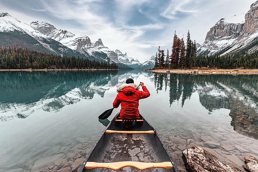 Male traveler in winter coat canoeing at Spirit Island on Maligne Lake in Jasper National Park, Alberta, Canada.