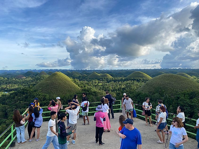 A crowd amassed atop a viewing platform overlooking grassy conical mountains that punctuate a jungle landscape in Bohol.