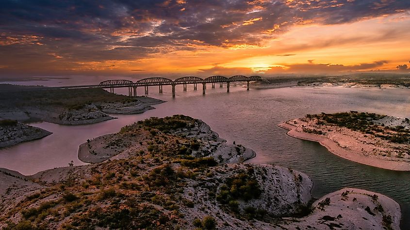 Aerial view of Amistad Reservoir and the Governor's Landing Bridge in Texas at sunset.