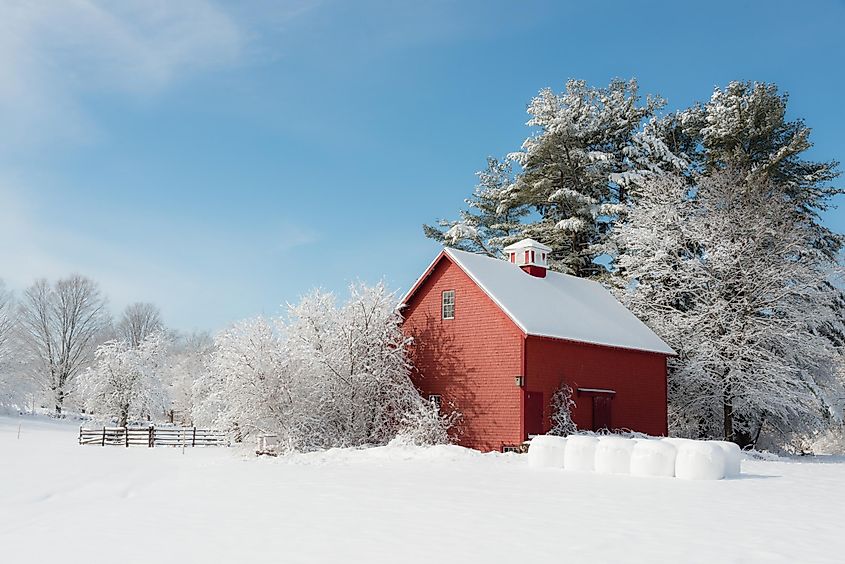 Winter in New England. Red farm building contrasting with white snow and blue sky. Ipswich, Massachusetts, USA