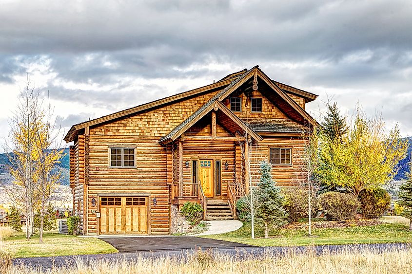 The exterior of a rustic log cabin, nestled at the base of the majestic Teton mountain range in Driggs, Idaho.