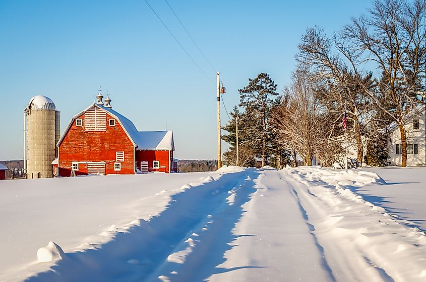 A path leads up a snowy hill where a red barn and white farm house stand near Pequot Lakes, Minnesota.