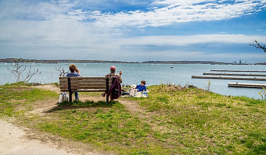 Family sitting on the shore in summer and watching the beautiful ocean view, in Portland, Maine