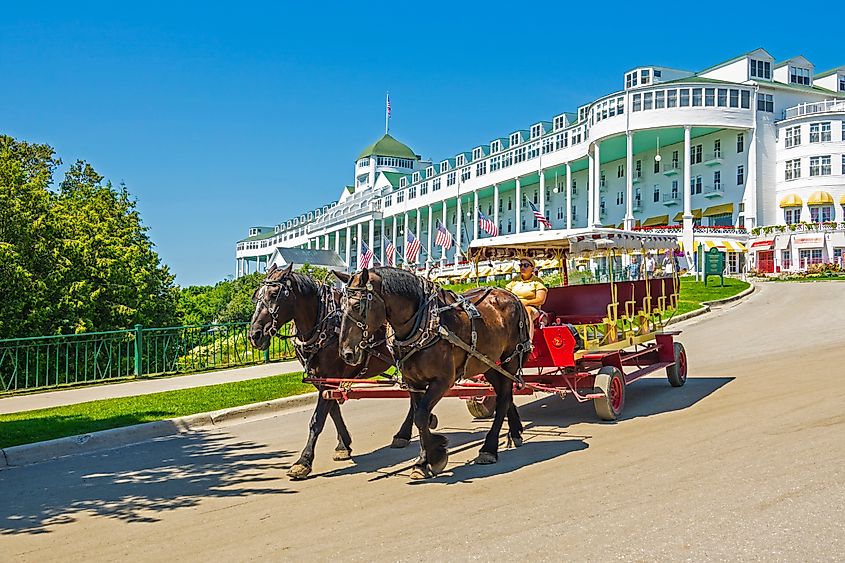 A horse-drawn carriage descends the driveway of the long, white, palatial Grand Hotel on Mackinac Island