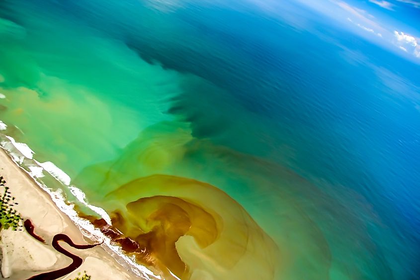 A river mouth discharging runoff into the ocean, the primary pathway by which land-based plastic waste enters the North Atlantic and other ocean basins.