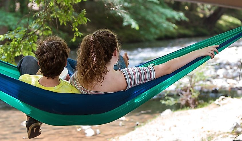 A teenage couple relaxes in a hammock while looking out at a river in Meeks Park in Blairsville, Georgia.