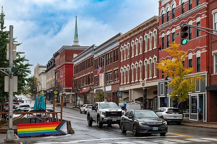 View of Main Street in downtown Bangor, Maine, featuring a mix of historic buildings and local businesses. The autumn setting adds to the charm of the bustling city center.