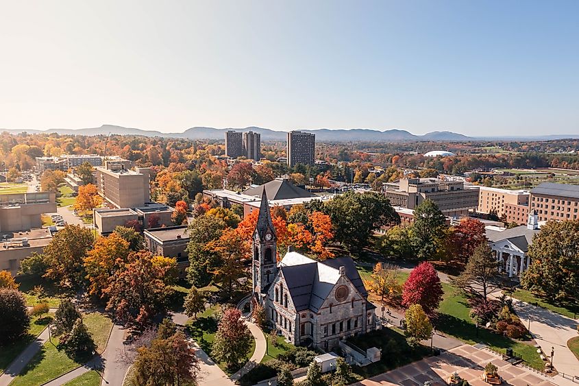 Aerial view of the University of Massachusetts Amherst campus on a sunny autumn day, with buildings surrounded by colorful fall foliage.