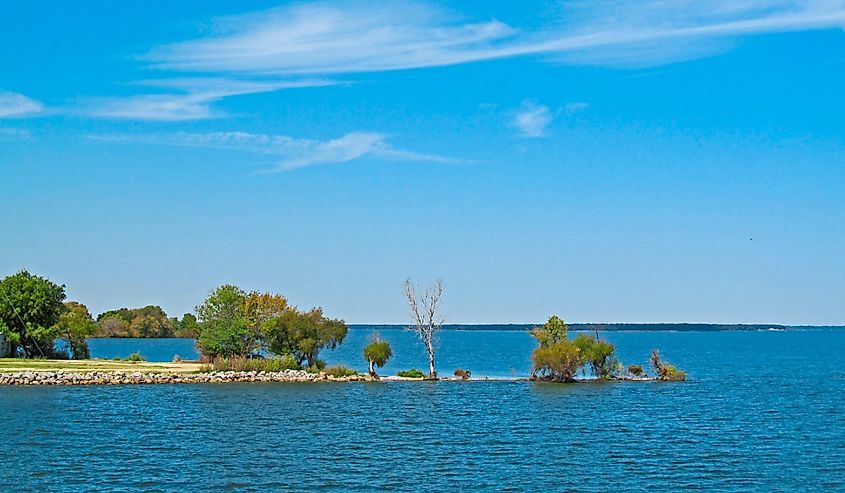 Bright view of Tawakoni Lake in Texas showing the surface of the water and the shore with green trees.