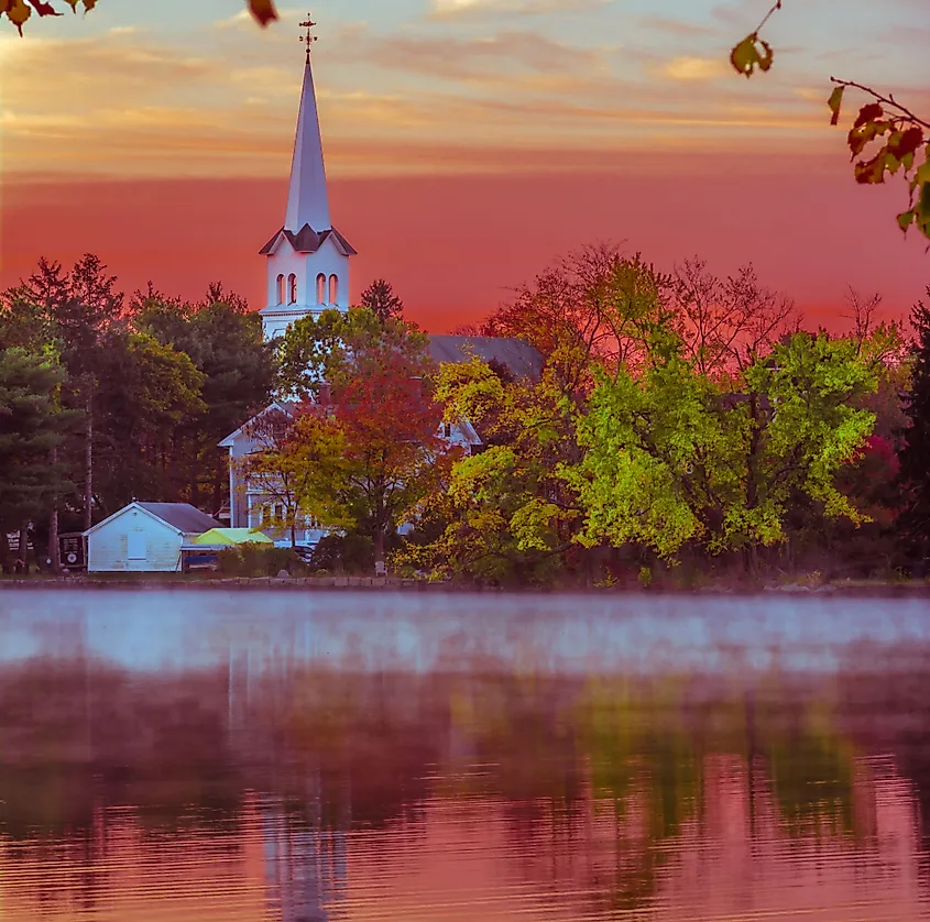 Sunset over a lake in Braintree, Massachusetts, reflecting a church and surrounding trees