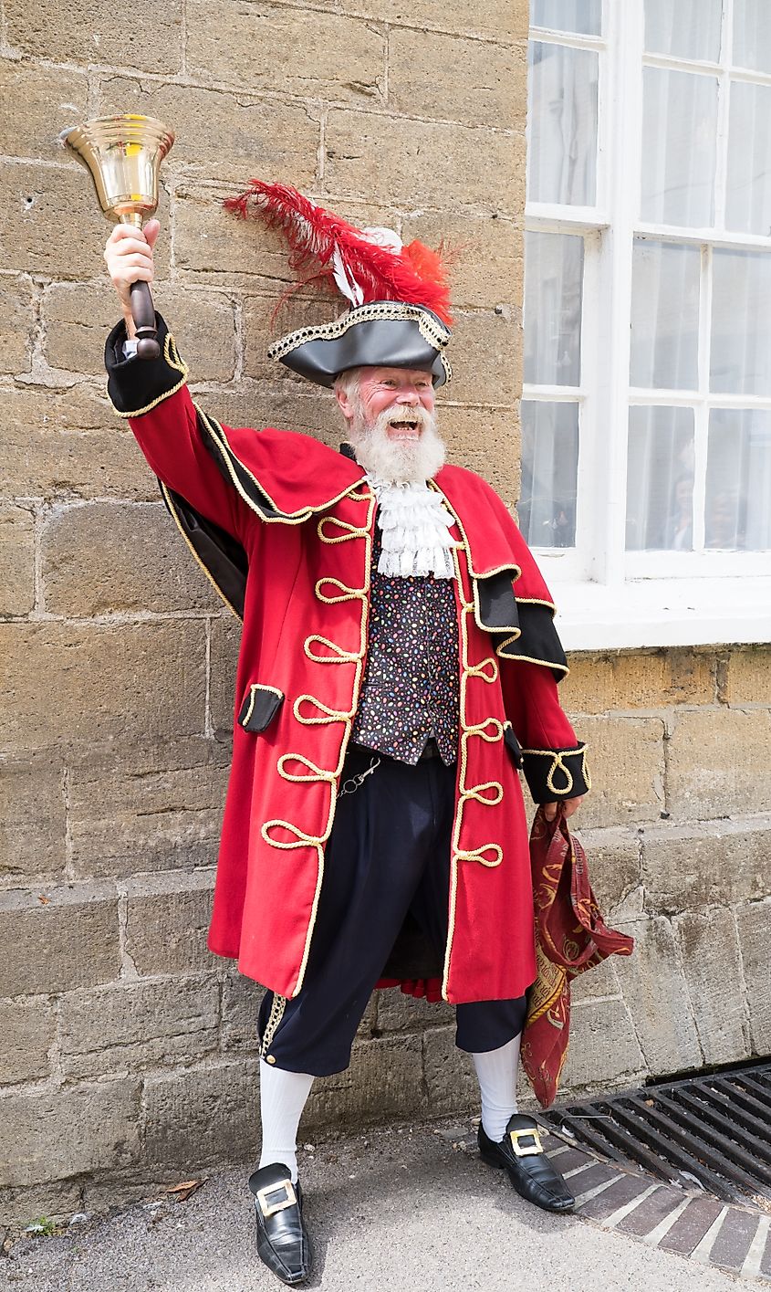 Man in a red and gold Town Crier costume entertains visitors on the streets of Bridport. Image by Johann Knox via Shutterstock.com