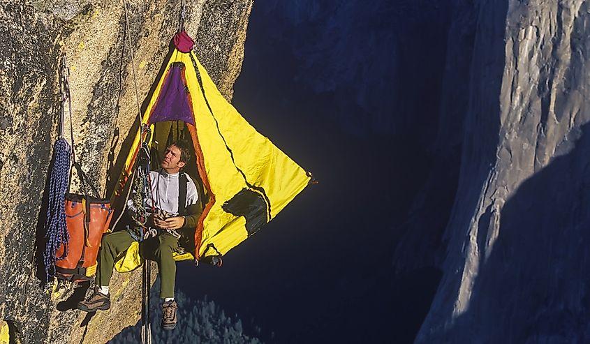 Climber in his hanging camp sleeps on the side of a mountain.