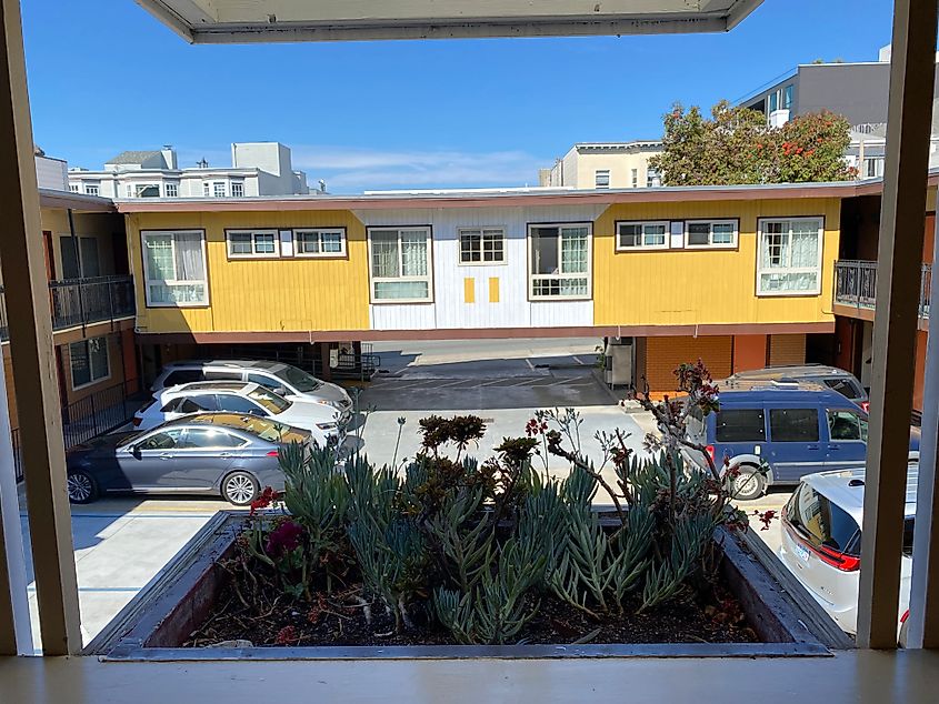 The inner parking lot of a yellow San Francisco motel.