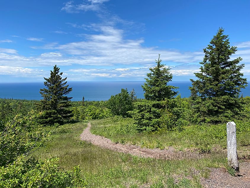 A trail leads down through green grass and trees of Michigan’s Brockway Mountain to the bold blue waters of Lake Superior