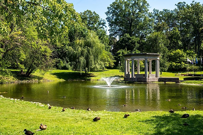 Horizontal view of historic Congress Park, a park with landscaped grounds, statuary, fountains, and a historic former casino building in Saratoga Springs.