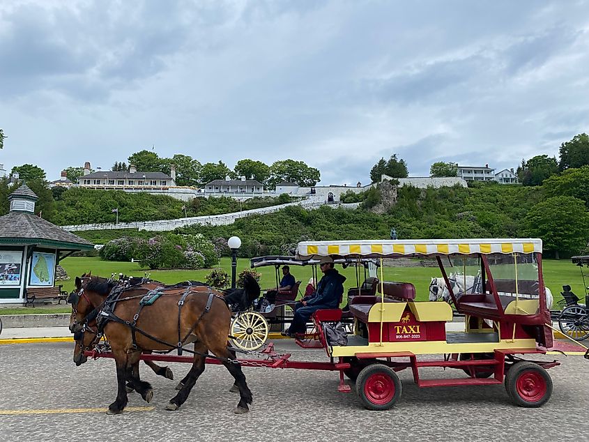 A horse-drawn carriage taxi passes beneath a huge hilltop fort.