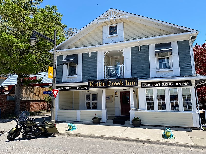 A motorcycle parked outside of a small and historic accommodation called the Kettle Creek Inn.