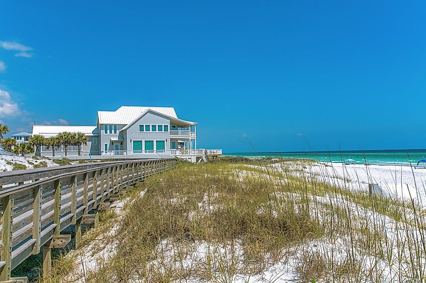 Boardwalk leading to a beach house on the white sands of Destin, Florida, with grasses and a terrace overlooking the shore.