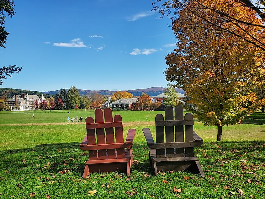 Two Adirondack chairs positioned to overlook a vibrant scene of Vermont foliage on the Middlebury College campus.