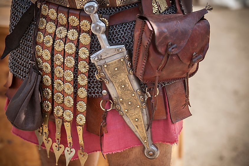 A Roman centurion girding a pugio, the small dagger worn by Roman soldiers as a sidearm, during a historical reenactment.