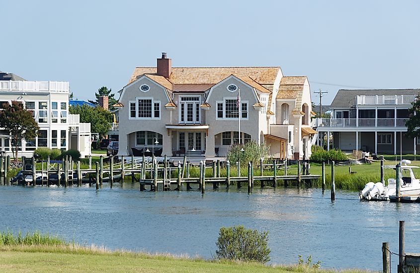 Houses line a canal in Lewes, Delaware, with docks, boats, and calm water in the foreground.