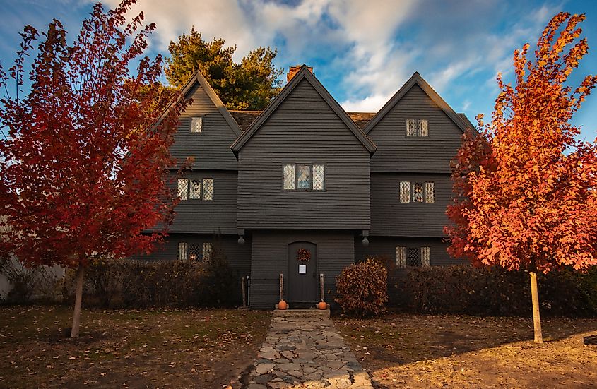 The Salem Witch House in Fall with bright red trees out front.