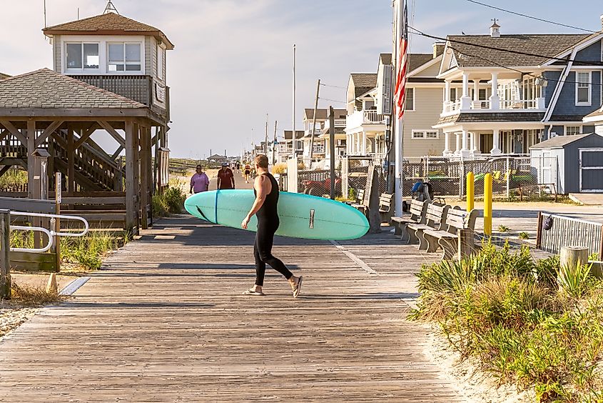 Surfer carrying a longboard on Lavallette boardwalk.
