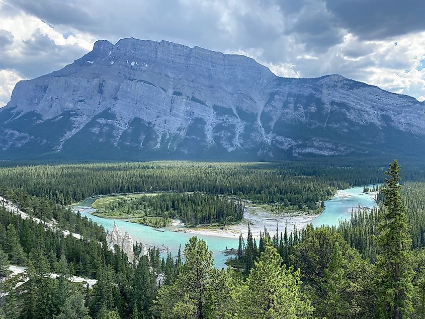 The long angular slope of Mount Rundle stands above the Bow River and its small collection of hoodoos in Banff National Park