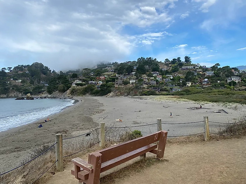 A bench overlooking a small, wild beach and the accompanying residential community of Muir Beach