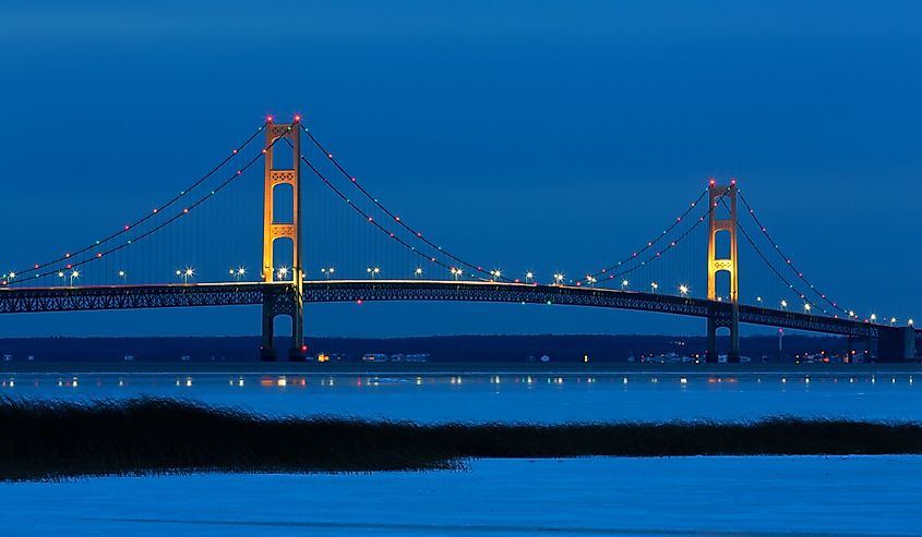 Blue Hour, just after sunset, creates an inviting backdrop for the Mackinac Bridge. Its lights twinkle and create reflections on winter ice