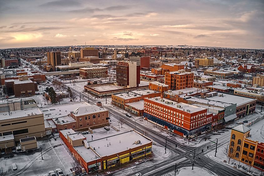 Aerial view of Cheyenne, Wyoming at dusk in winter, with snow-covered rooftops and softly lit streets.