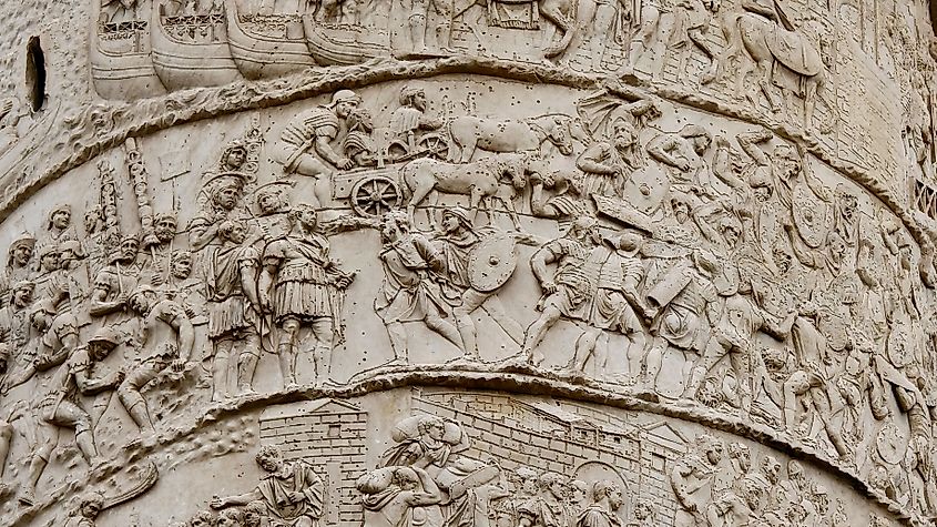 A relief on Trajan's Column shows Roman troops advancing with oxen-pulled carts, weapons, and civilians during a campaign.
