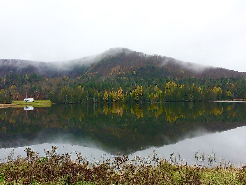 Runaway Pond in Grover, Vermont, a serene body of water surrounded by dense forest and rolling hills.