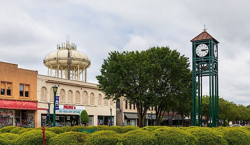 View of town clock, water tower and block of vintage store buildings across line of shrubbery, Thomasville, North Carolina.