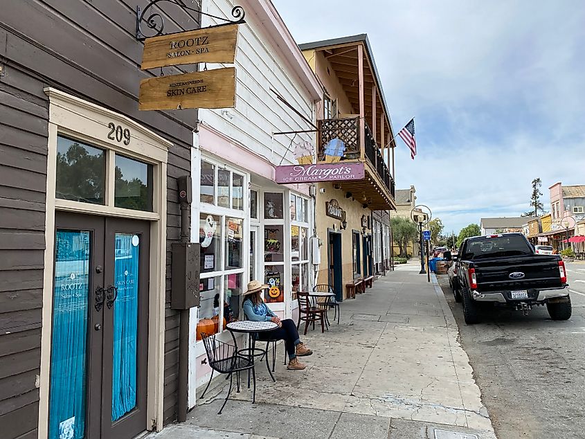 A woman relaxes at a sidewalk table in small Western/Spanish influenced California town.