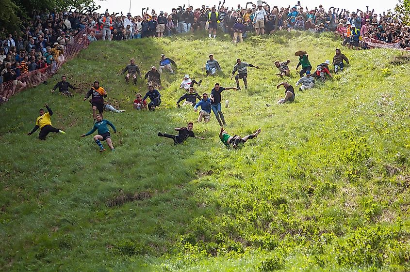 Competitors tumble down the steep slope at the Cooper's Hill cheese-rolling event. Editorial credit: JessicaGirvan / Shutterstock.com