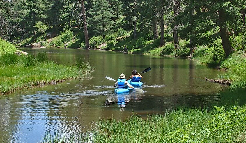 A couple in blue canoes paddling on Woods Canyon Lake on the Mogollon Rim east of Payson in Arizona