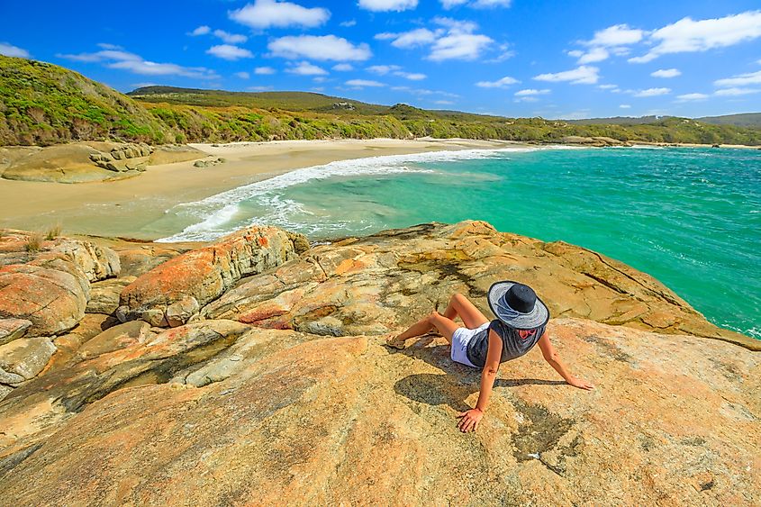 Woman in hat sunbathing on the rocks of Waterfall beach in Denmark, Western Australia.
