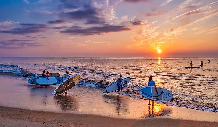 A group of young women who most mornings during the summer months take their paddle boards out at sunrise to paddle several miles up or down the coast, Bethany Beach, Delaware